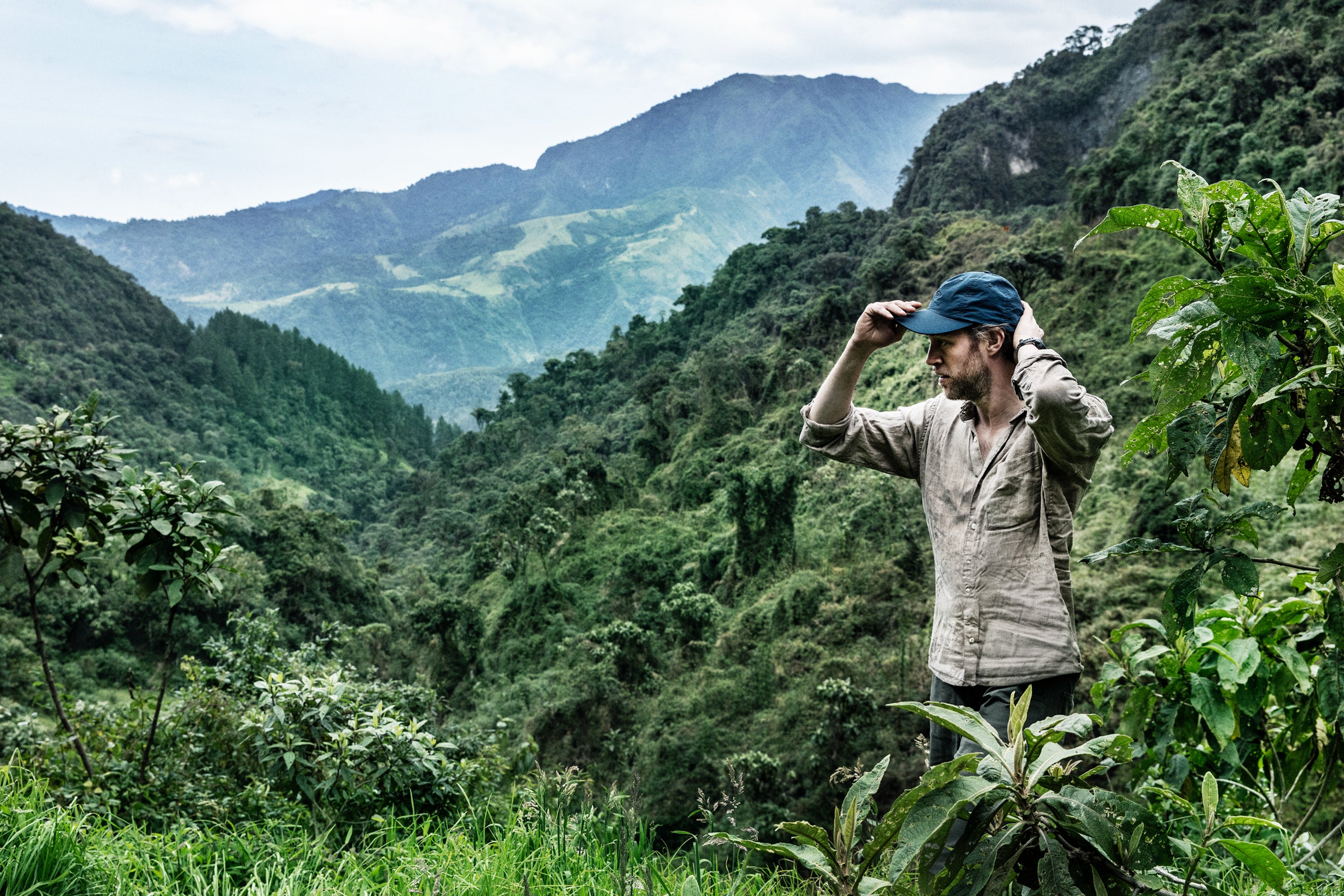 Person standing in a lush green valley with mountains in the background