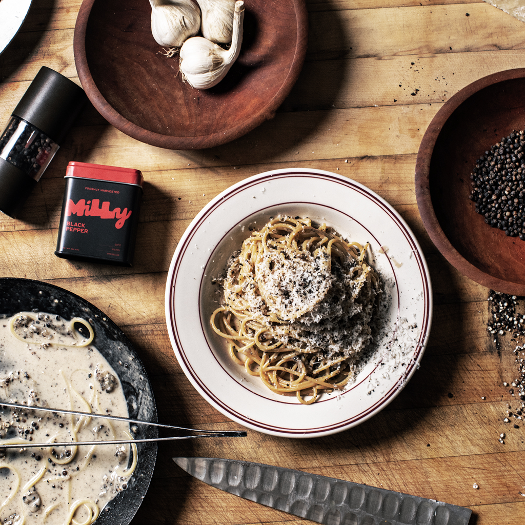 Spaghetti dish on a wooden table with garlic and a can of black truffle oil.